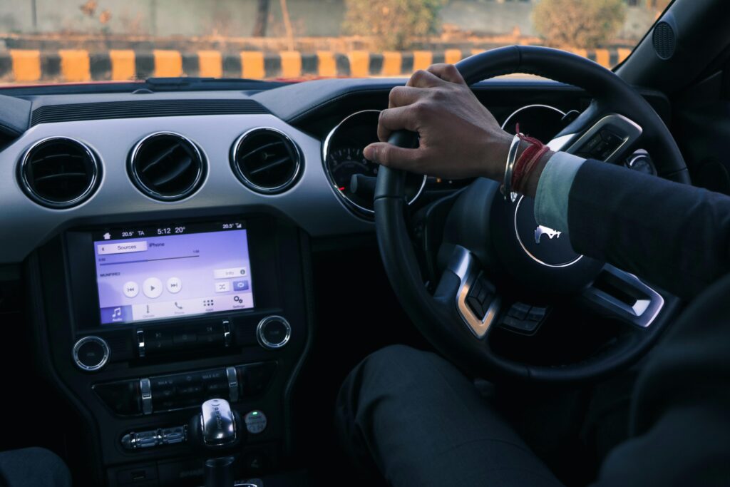 Close-up of a car interior with driver's hand on steering wheel in Delhi, India.